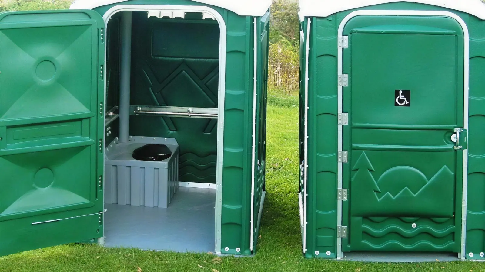An accessible portable toilet with its wide door open, showing the grab rail, seat and level floor inside