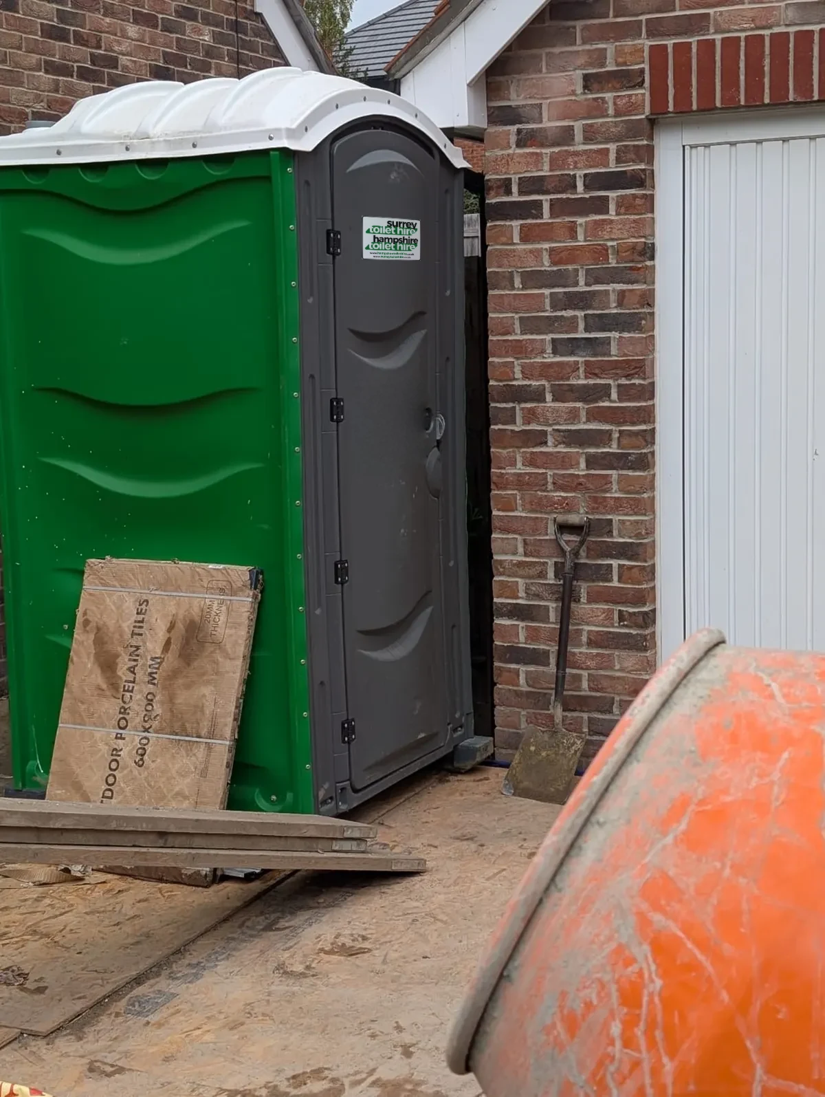 One of our green site toilets on a house build, with our Surrey and Hampshire Toilet Hire sign on the door