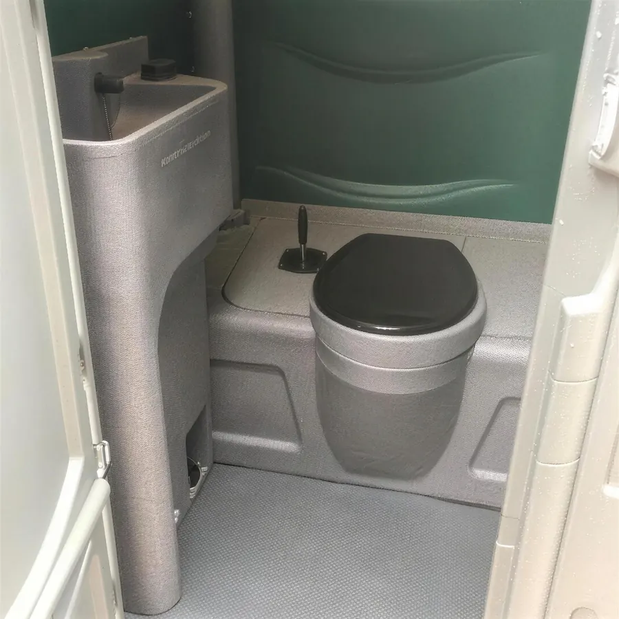 The inside of one of our portable toilets: a hand basin beside a black seat